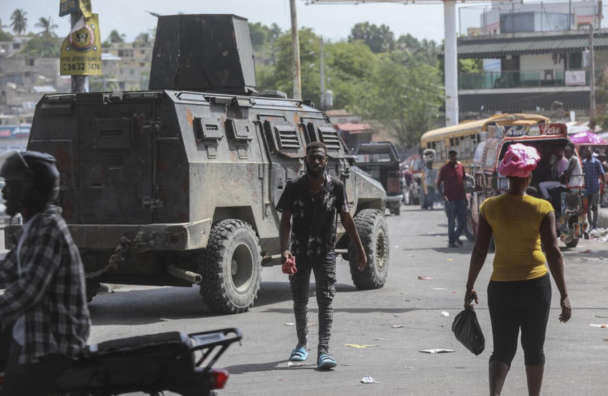 People walk past an armored police vehicle patrolling the streets in Port-au-Prince, Haiti.