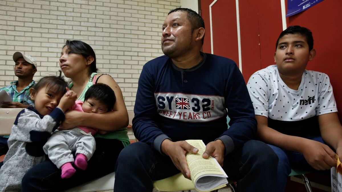 Miguel Rodas. center, and his son, Samuel, right, of El Salvador, listen to information about their court hearings, that will occurring in coming months. At left are Faviola, the mother of 2-month-old Kimberly, and Genesis, 3.