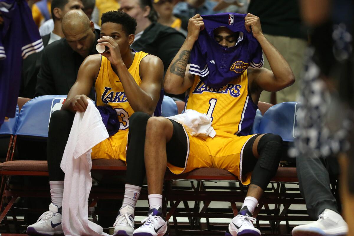 Lakers guard D'Angelo Russell pulls on his warmup shirt as he sits on the bench with teammate Anthony Brown during an Oct. 22 exhibition game against the Golden State Warriors at Honda Center in Anaheim.