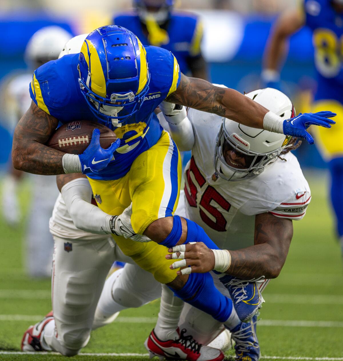 The Rams' Kyren Williams (23) tries to runs through the tackle of the Cardinals  Dante Stills (55).