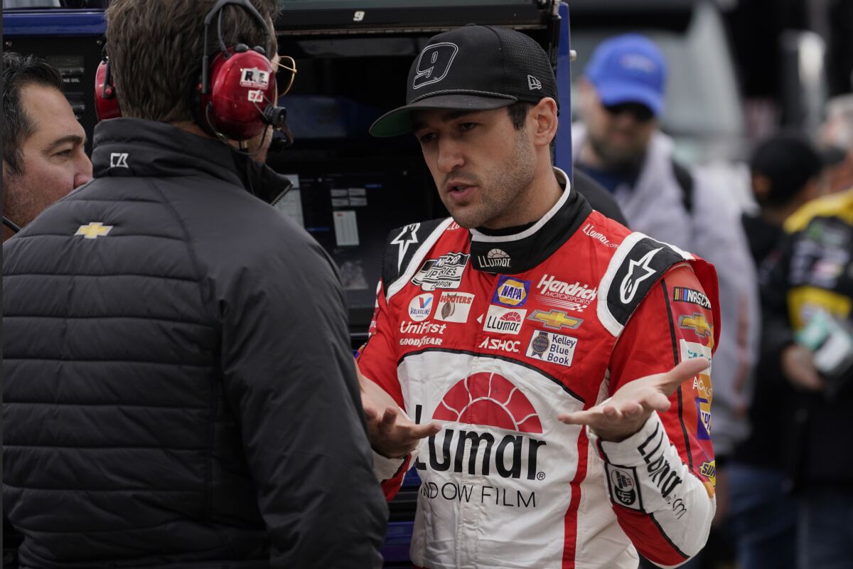 Chase Elliott talks with a team member prior to qualifying for Saturday's NASCAR Cup Series auto race at the Martinsville Speedway Friday April 8, 2022, in Martinsville, Va. (AP Photo/Steve Helber)