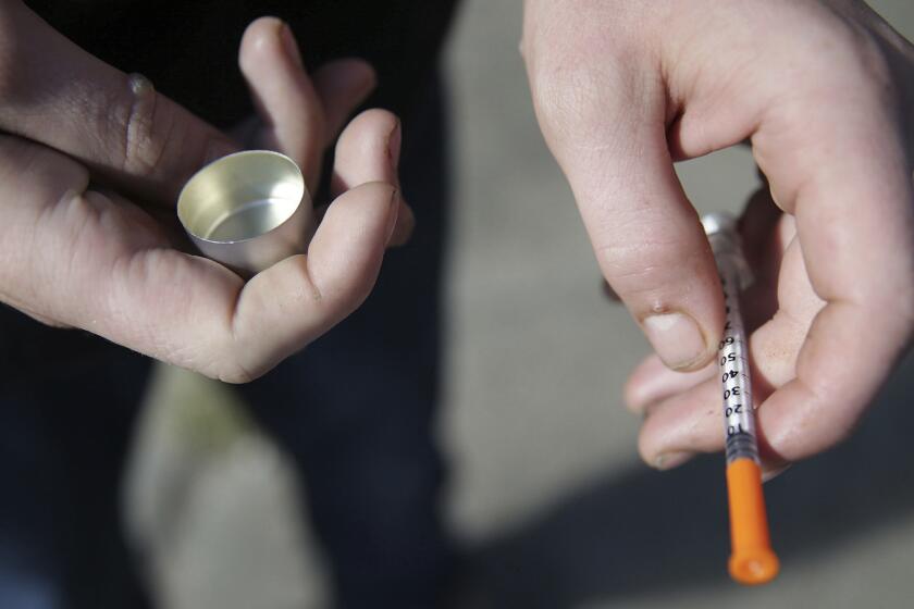 In this Oct. 22, 2018 file photo, a fentanyl user holds a needle near Kensington and Cambria in Philadelphia. Suicides and drug overdoses helped lead a surge in U.S. deaths last year, and drove a continuing decline in how long Americans are expected to live. U.S. health officials released the latest numbers Thursday, Nov. 29. Death rates for heroin, methadone and prescription opioid painkillers were flat. But deaths from the powerful painkiller fentanyl and its close opioid cousins continued to soar in 2017. (David Maialetti/The Philadelphia Inquirer via AP, File)