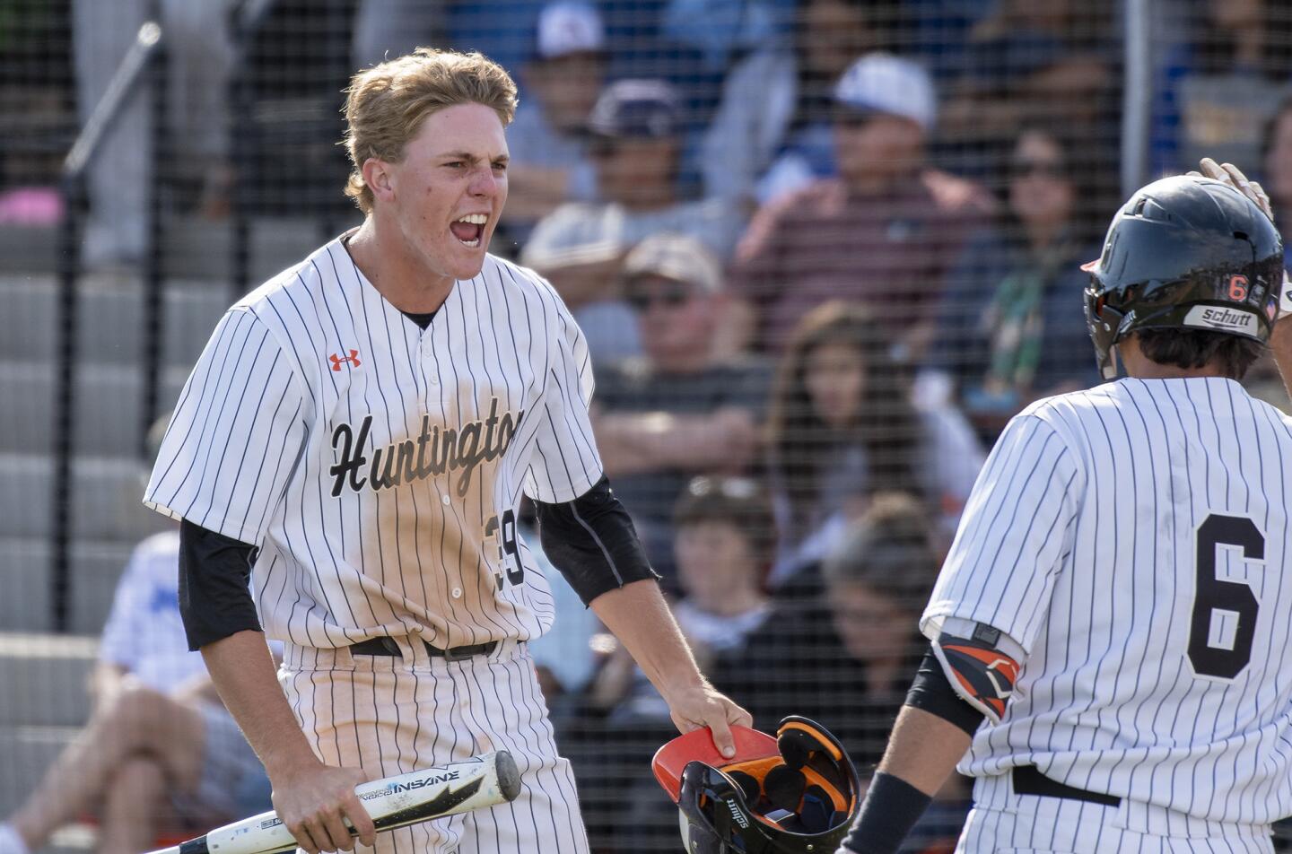 Huntington Beach High's Jag Burden, left, celebrates after scoring on a single by Jake Vogel in the sixth inning of a CIF Southern Section Division 1 second-round playoff game against Bishop Amat on Tuesday.