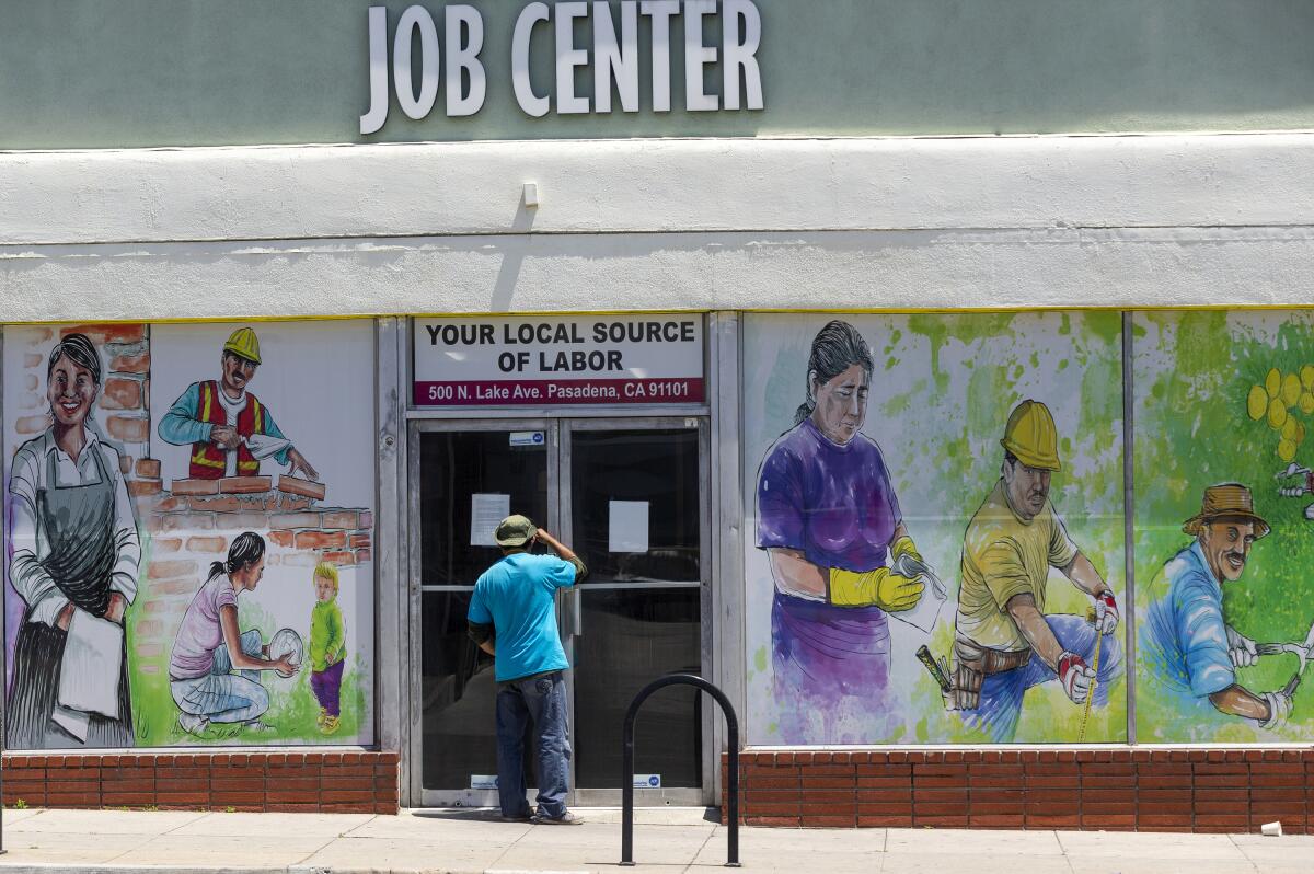 A person looks inside the closed doors of the Pasadena Community Job Center in May 2020. 