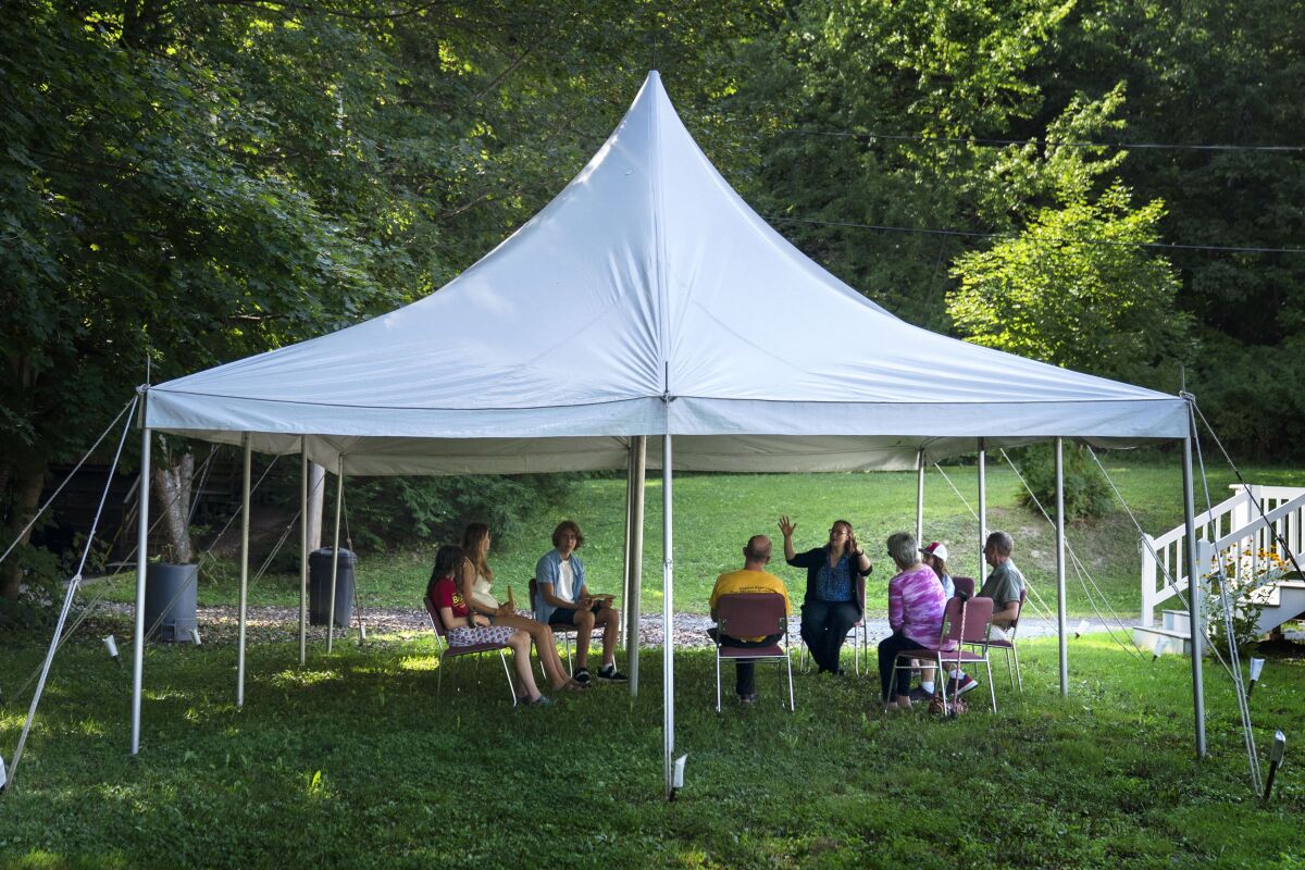 A class in Judaism is held under a tent set upon outside Temple Beth El, Monday, Aug. 30, 2021, in Augusta, Maine. The recent COVID-19 upsurge is disrupting plans for full-fledged in-person services. “The ability to see people face to face is wonderful, whatever way they choose to come,” Rabbi Erica Asch says. “But there’s a little bit of sadness that we can’t all be together the way we’d like.” (AP Photo/Robert F. Bukaty)