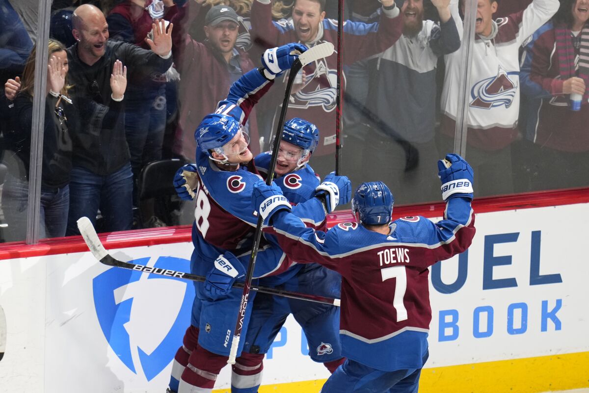 Colorado Avalanche defenseman Cale Makar (8) is congratulated by center Nico Sturm (78) and defenseman Devon Toews (7) after scoring the against the Nashville Predators during overtime in Game 2 of an NHL hockey Stanley Cup first-round playoff series Thursday, May 5, 2022, in Denver. The Avalanche won 2-1. (AP Photo/Jack Dempsey)