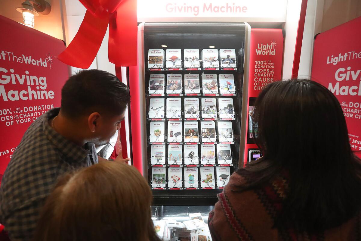 A family chooses an option from the Giving Machines at Pacific City in Huntington Beach on Tuesday.