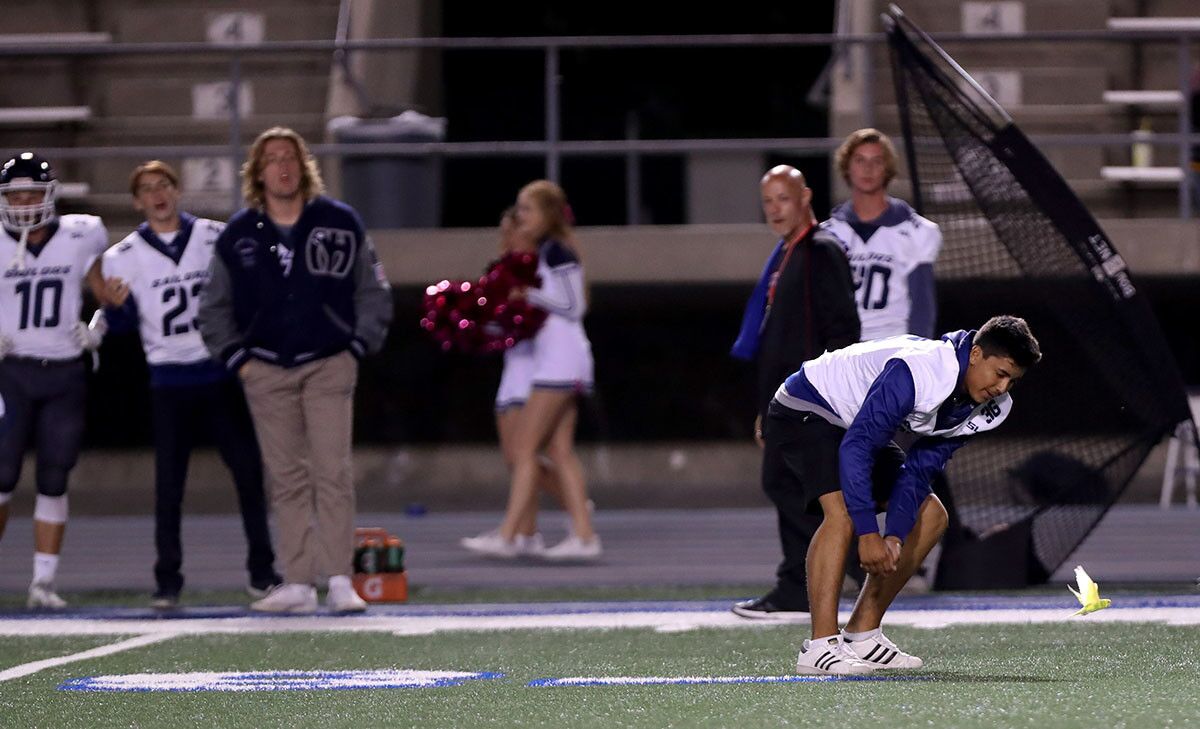 A Newport Harbor High School football player tries to catch a parakeet that flew onto the field in the second half of away game vs. Los Alamitos High School, at Cerritos College in Norwalk on Friday, Oct, 5m 2018. NHHS lost 7-42.