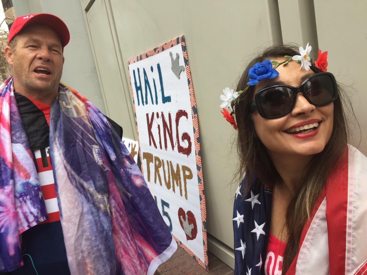 John Turano and his daughter, Bianca, wrap themselves in flags while waiting for President Trump in downtown Los Angeles.