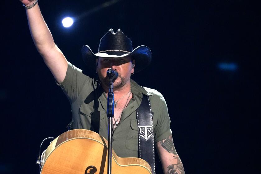 Onstage with his guitar, Jason Aldean points his finger to the sky
