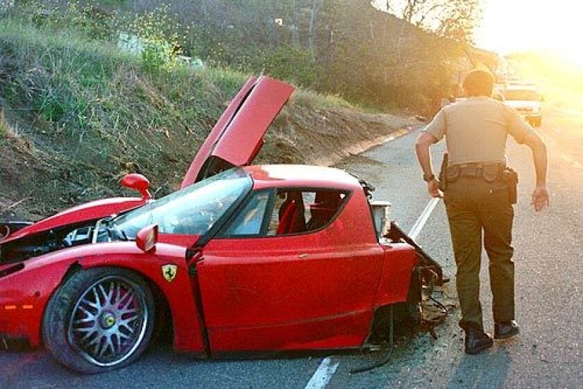A deputy passes the wrecked Ferrari that crashed on Pacific Coast Highway west of Decker Canyon Road. The car's registered owner, Swedish millionaire Stefan Eriksson, said that he was a passenger. On Monday, he was charged with grand theft, embezzelment and a firearms violation.