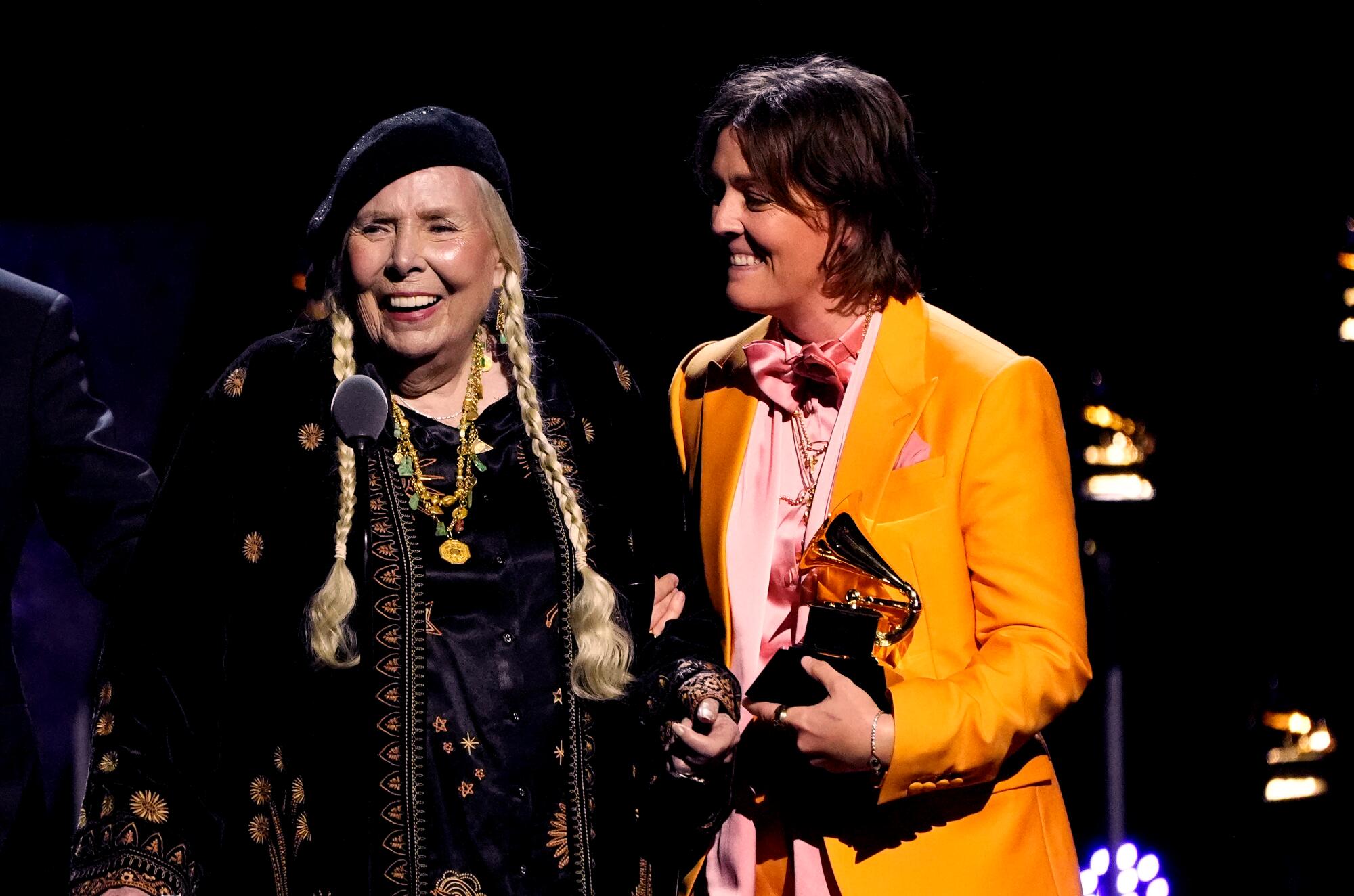 Joni Mitchell, left, accepts the award for best folk album during the 66th Annual Grammy Awards