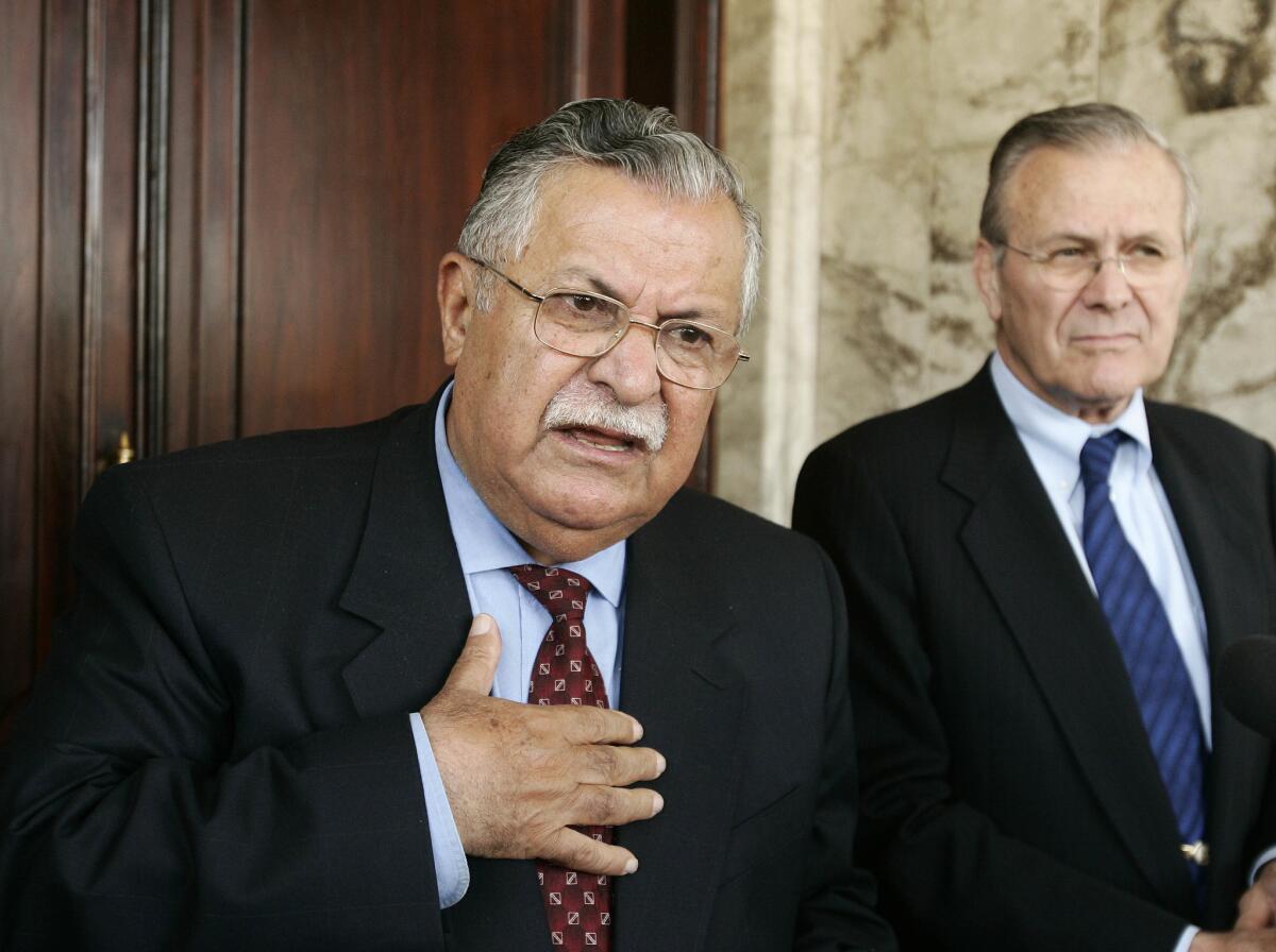 Former Iraqi President Jalal Talabani and then-Secretary of Defense Donald Rumsfeld talk at a news conference in Baghdad on April 12, 2005.