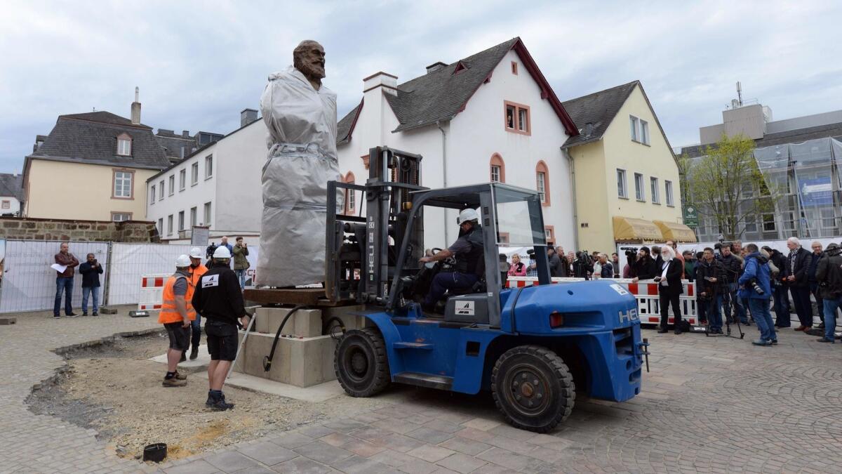 Workers install a statue of German philosopher, economist, political theorist and sociologist Karl Marx on April 13, 2018, in Trier, Germany. The statue by Chinese artist Wu Weishan will be fully unveiled on May 5, Marx's 200th birthday.