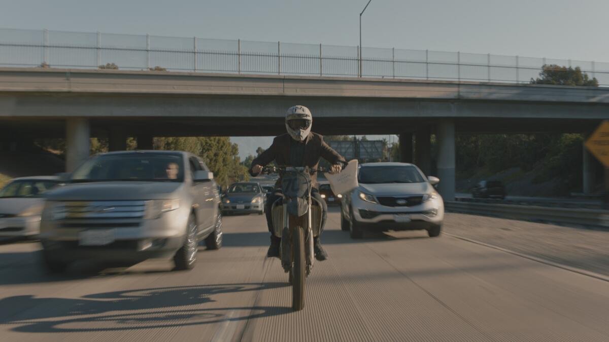 A man rides a motorbike on the freeway carrying a bag of baked goods.