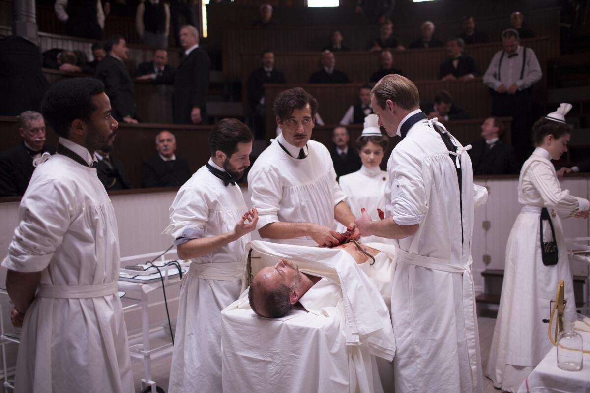 Four doctors and two nurses work on a patient on a gurney in an operating theater