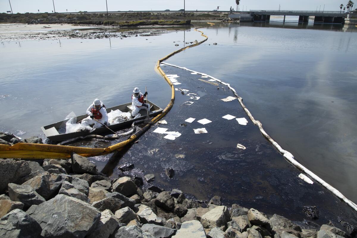 Workers with Patriot Environmental Services clean up oil that flowed into the Talbert Marsh in Huntington Beach. 