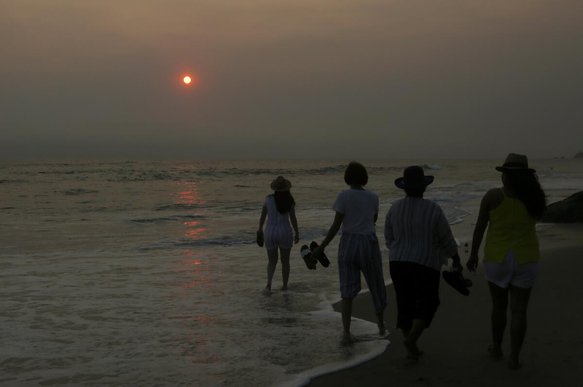 Beachgoers walk the rocks at Cress Street in Laguna Beach.