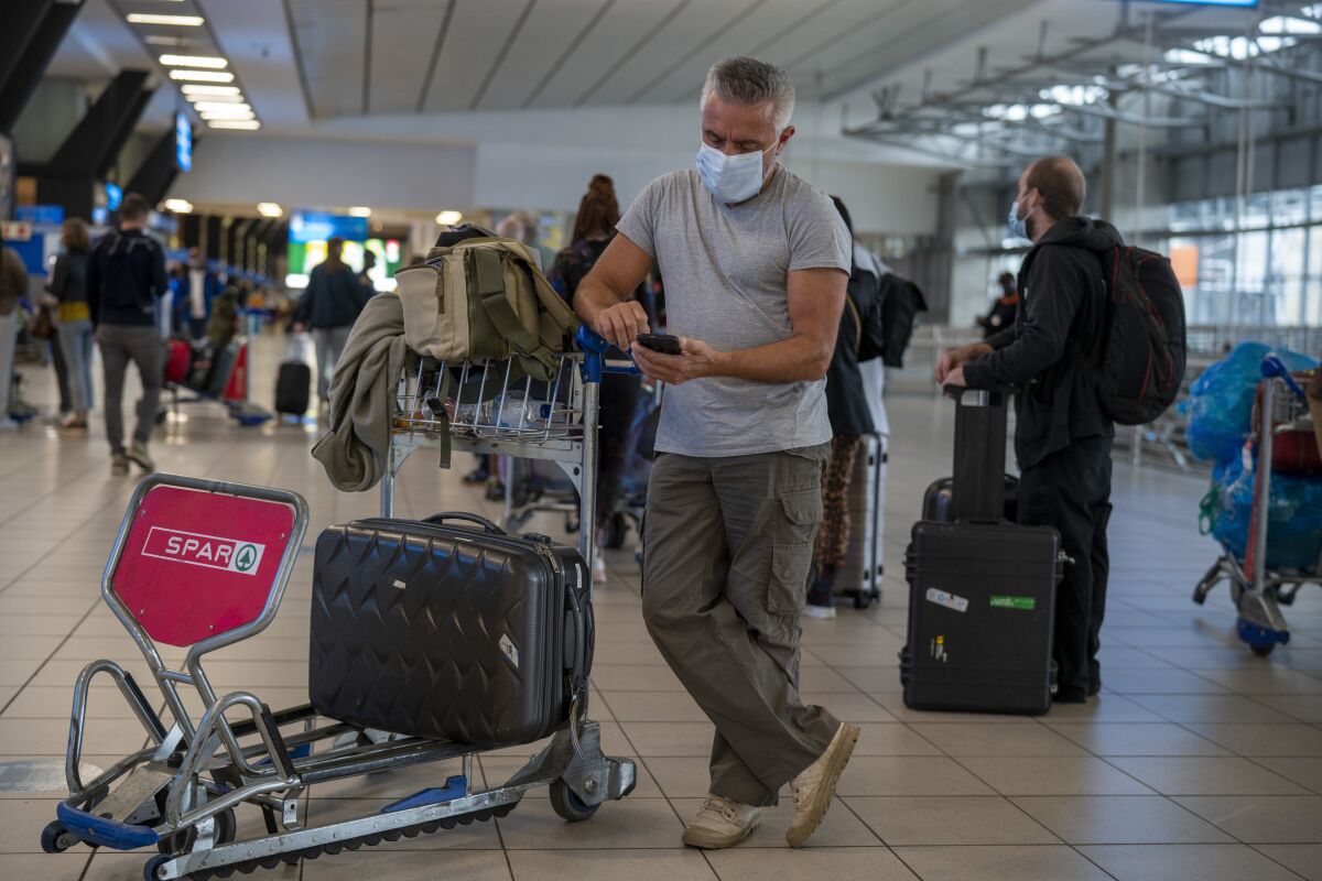 A traveler checks his phone while waiting with others for their flights in an airport terminal.