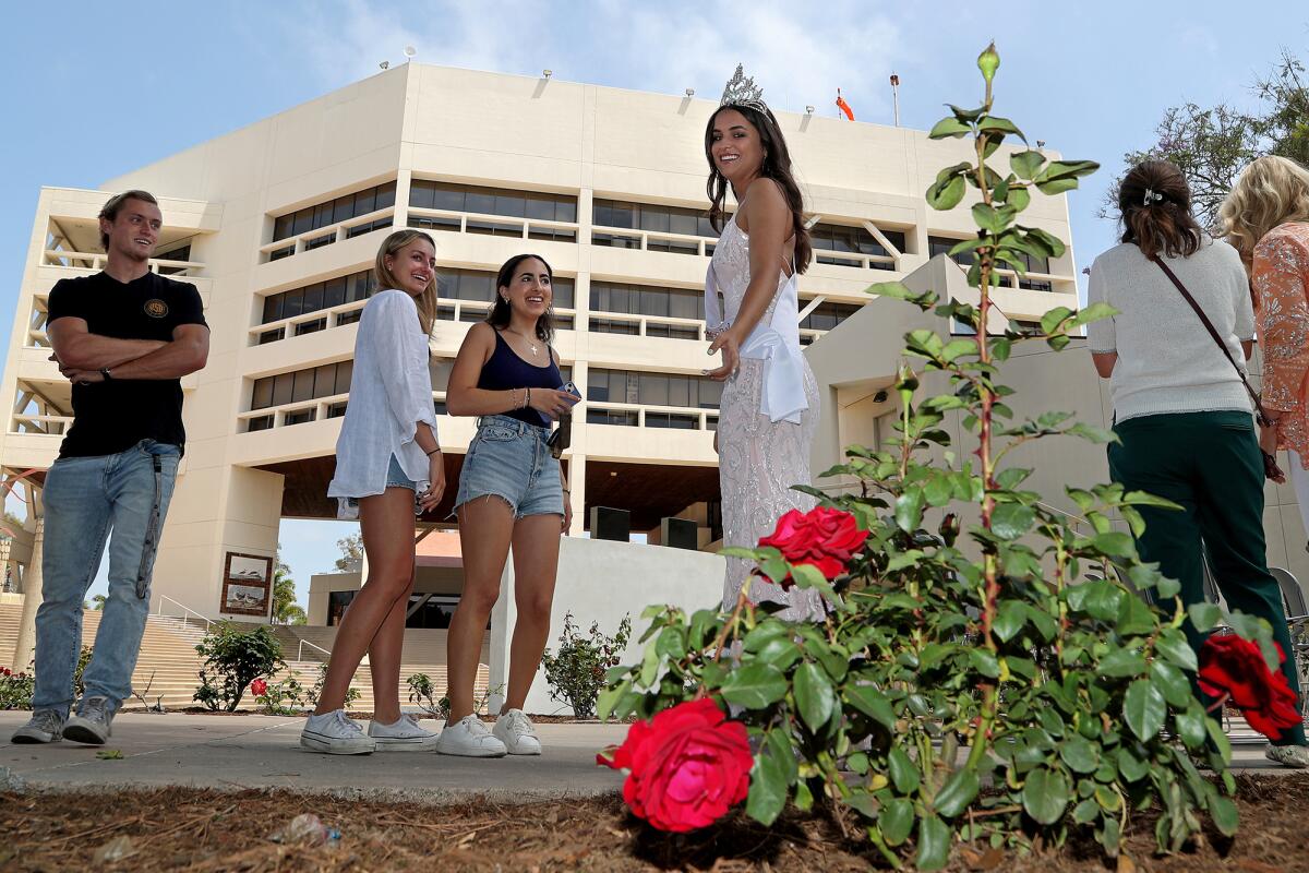 Queen Gisell Gochman, 19, right, shows her rose bush to her friends before the start of Wednesday's ceremony. 