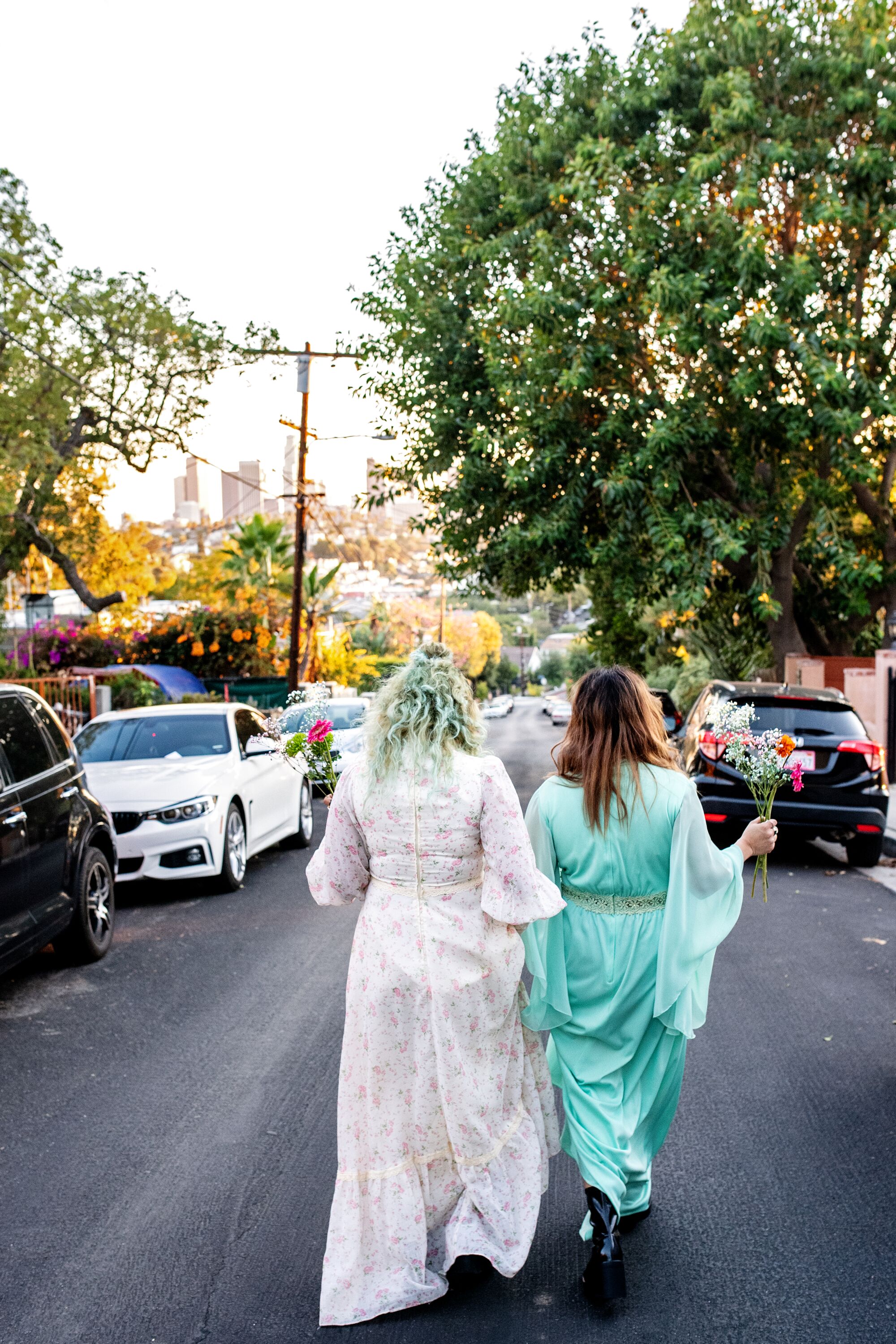 Ursula and Rebecca Recinos walk down the street, their backs to us, flowers in hand.