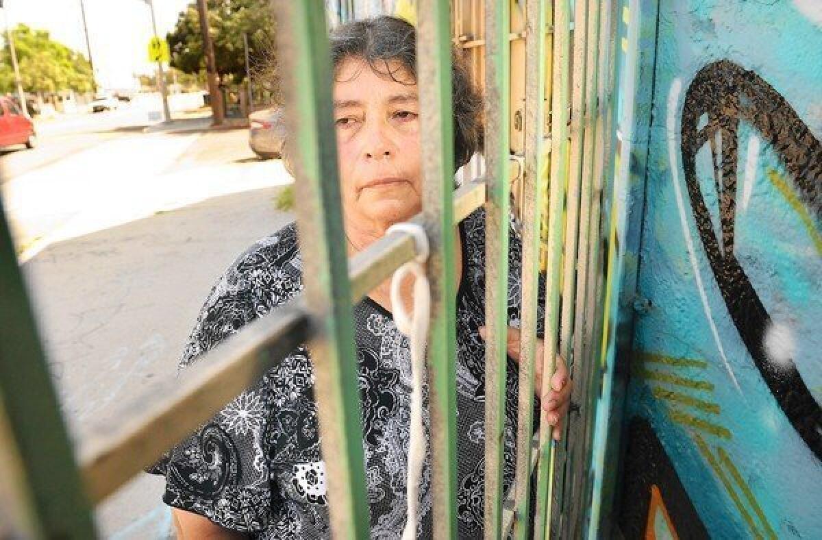 Francisca Pena stands outside the store where her husband was shot to death in 1990. The LAPD recently found DNA evidence linking a suspect to the crime.