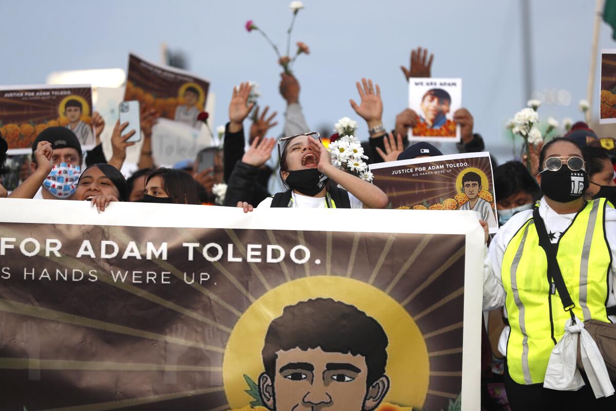 Protesters hold a banner with a drawing of Adam Toledo.