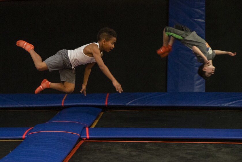 Two boys bounce at a trampoline park.