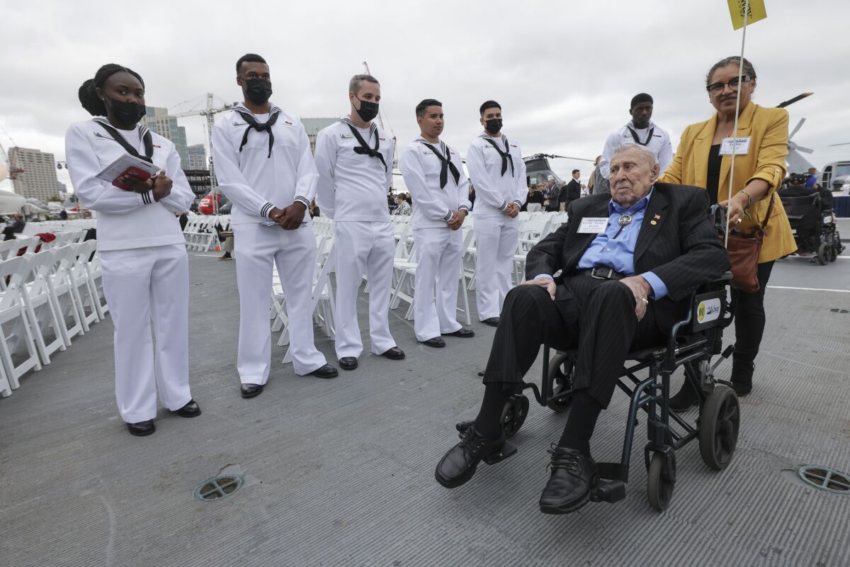 Navy sailors stand in line as Battle of Midway veteran Ervin "Judge" Wendt is taken past them