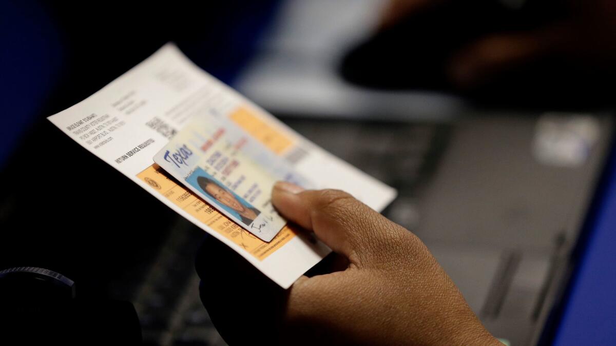 An election official checks a voter's photo identification at a polling site in Austin, Texas in Feb. of 2014.