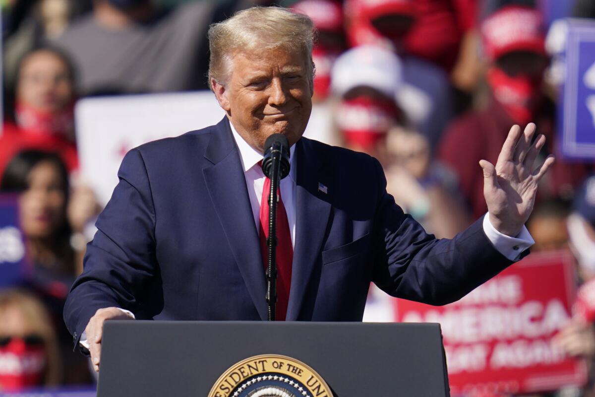 President Donald Trump speaks at a lectern and waves