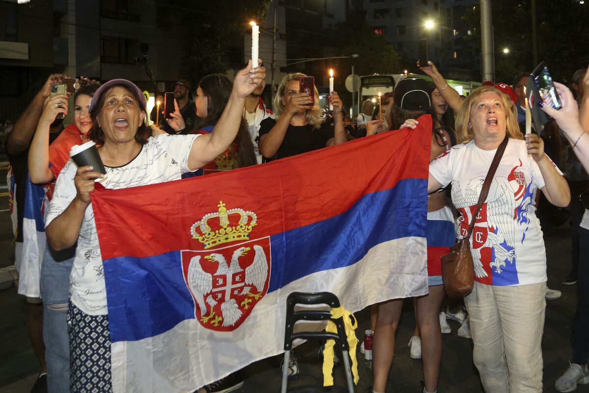 Supporters of Novak Djokovic protest and sing with candles outside a quarantine facility.