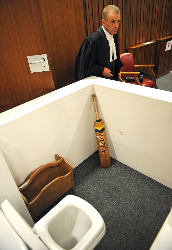 State prosecutor Gerrie Nel, alongside a reconstruction of a toilet cubicle, through which Oscar Pistorius shot and killed his girlfriend, Reeva Steenkamp on St. Valentine's day in 2013.