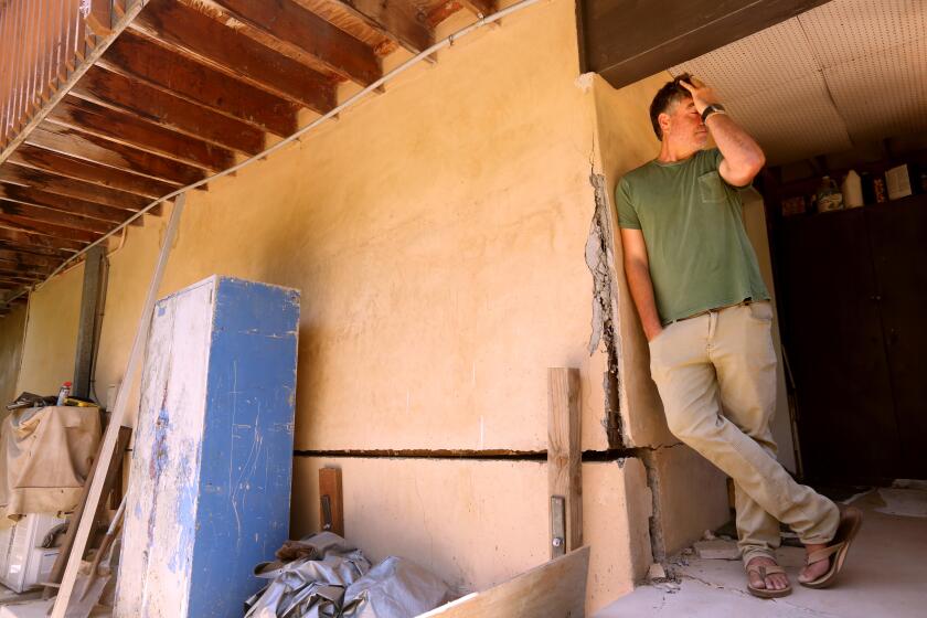 Denny Jaconi standing next a damaged portion of his home caused by the ongoing landslide.