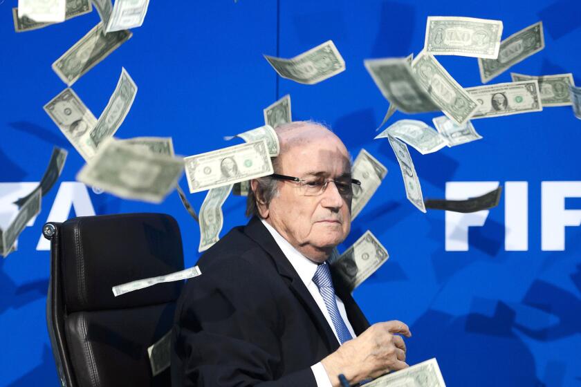 FIFA President Sepp Blatter reacts after a British comedian interrupted a news conference in Zurich on July 20 by throwing fake dollar bills.