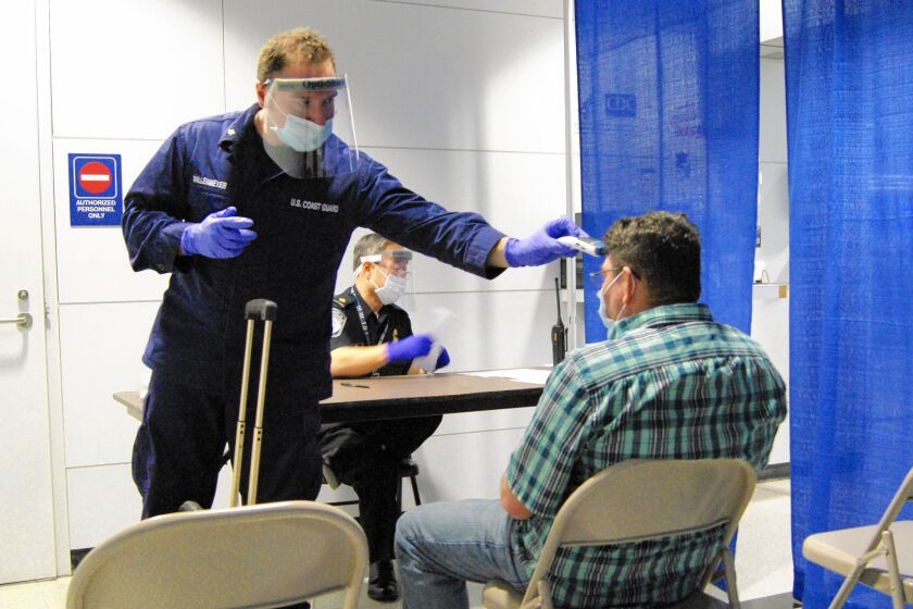 U.S. Coast Guard health technician Nathan Wallenmeyer, left, and customs supervisor Sam Ko screen a passenger from Sierra Leone at O'Hare International Airport in Chicago.