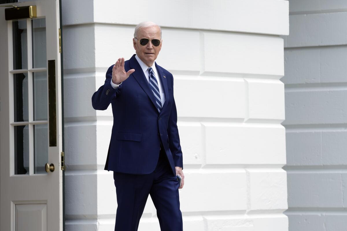 President Biden waves as he walks out of the White House.