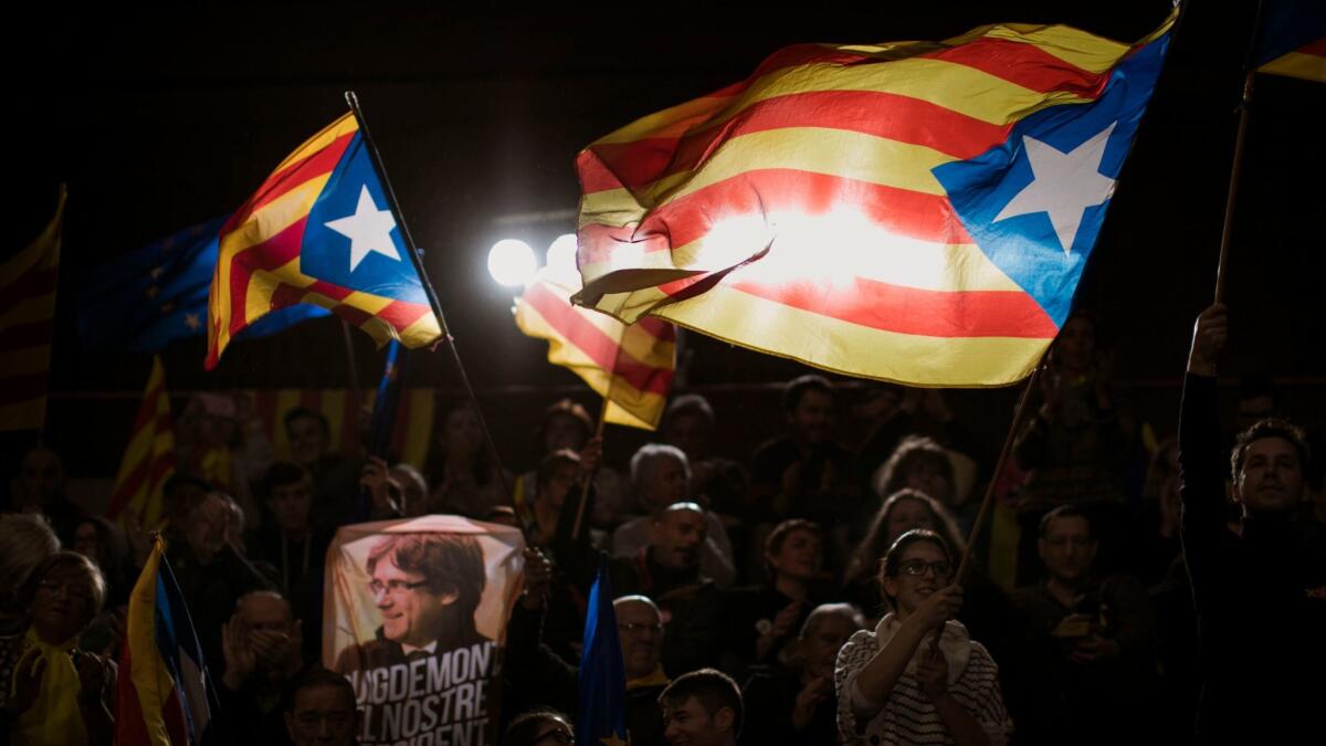 Supporters of leader Carles Puigdemont wave independence flags during the Catalan regional election campaign in Barcelona.
