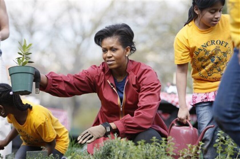 First lady Michelle Obama plants herbs in the White House Kitchen Garden with students from Bancroft Elementary School in Washington, Thursday, April 9, 2009, on the South Lawn of the White House in Washington. (AP Photo/Charles Dharapak)