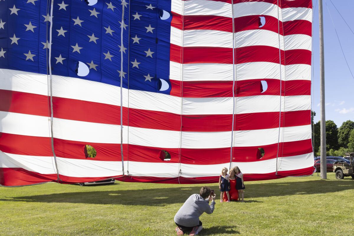 People pose in front of a giant flag on display outside the National Flag Foundation in Waubeka, Wis.