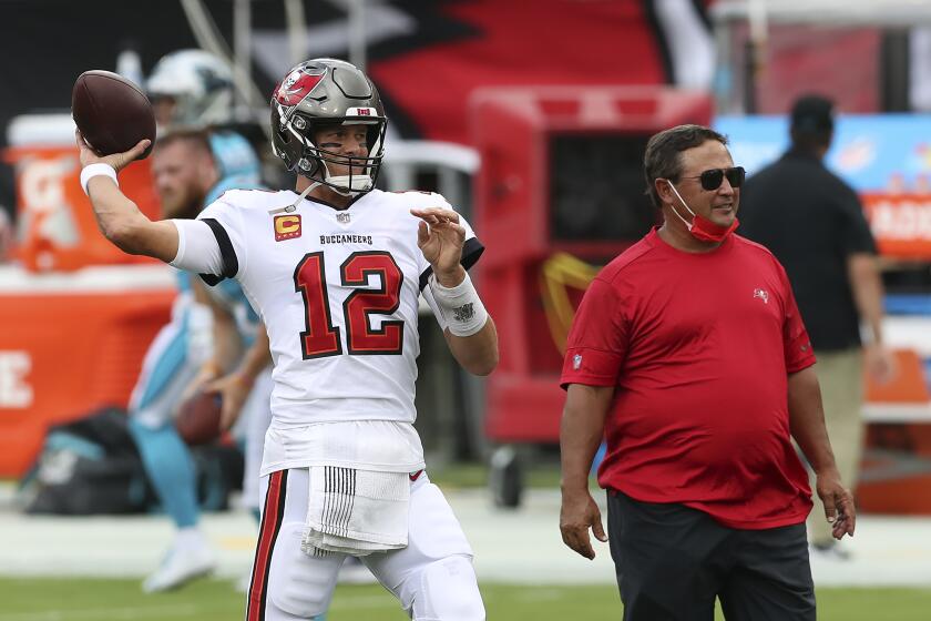 Tampa Bay Buccaneers quarterback Tom Brady (12) throws a pass as quarterback's coach Clyde Christensen looks on before an NFL football game against the Carolina Panthers Sunday, Sept. 20, 2020, in Tampa, Fla. (AP Photo/Mark LoMoglio)
