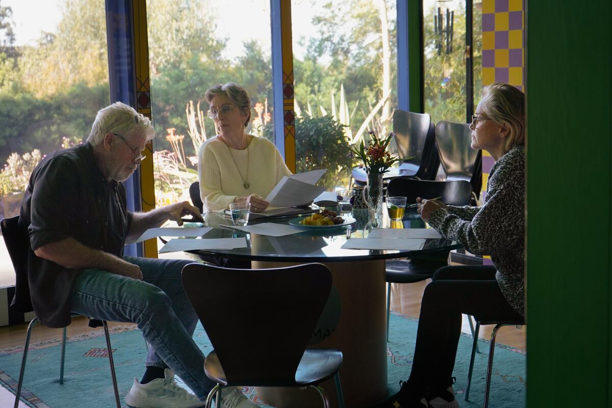 Three people sitting at a dining table, reading a story together.