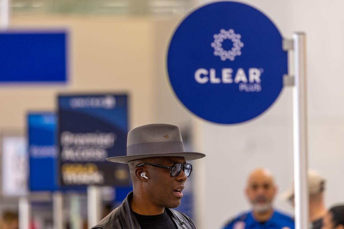 A passenger stands in Clear Plus line that gets him to gate faster, using eyes or fingerprints to 