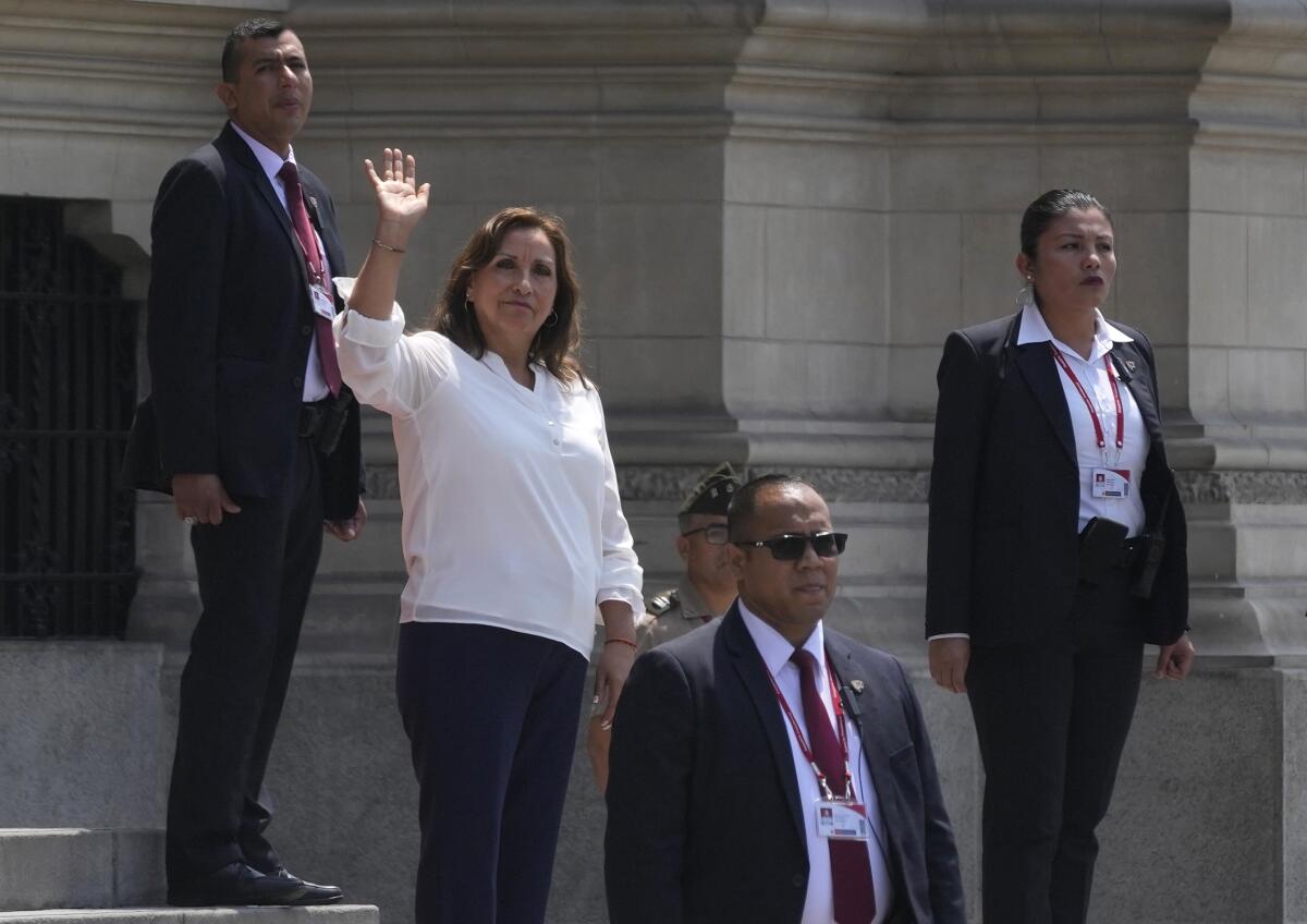 Rodeada de agentes de seguridad, la presidenta de Perú, Dina Boluarte, saluda a la prensa