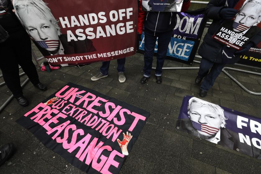FILE - In this Thursday, Jan. 23, 2020 file photo, demonstrators supporting Julian Assange hold banners outside Westminster Magistrates Court in London. WikiLeaks founder Julian Assange is set to fight for his freedom in a British after a decade of legal drama, as he challenges American authorities’ attempt to extradite him on spying charges over the site’s publication of secret U.S. military documents. Lawyers for Assange and the U.S. government will face off in London Monday, Sept. 7, 2020 at an extradition hearing that was delayed by the coronavirus pandemic. (AP Photo/Kirsty Wigglesworth, File)
