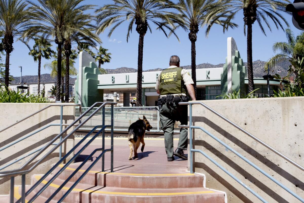 A Los Angeles County Sheriff's deputy and K-9 walk through the Burbank train station which was closed due to a report of a possible bomb on a Metrolink train.
