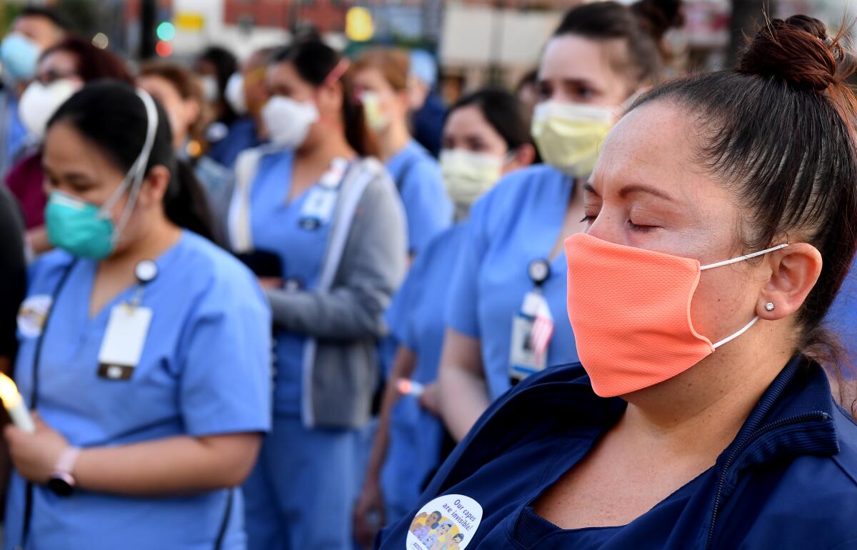 Health workers wear medical scrubs and masks during a vigil