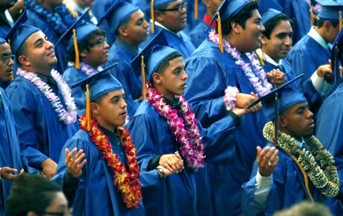 Ricardo, left, and Robert Placensia hold hands durng the recitation of the Lord's Prayer during their Verbum Dei High School graduation ceremony at the Cathedral of Our Lady of Angels in Los Angeles.