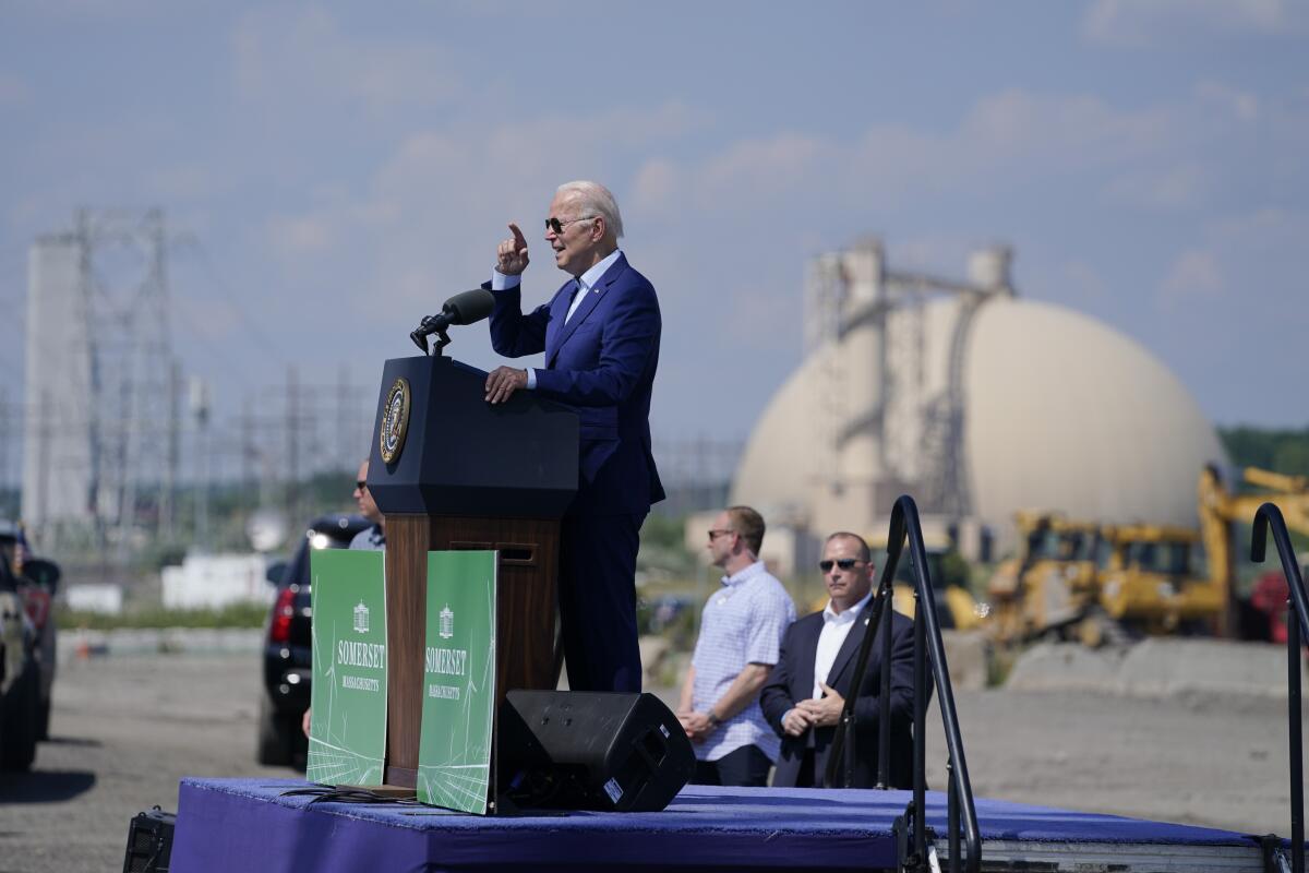President Biden speaks at a lectern near a power station.