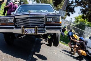 National City, CA - June 17: Attendees observe the hydraulics of a Black Cherry Cadillac Broham owned by Mike Gonzales parked at Kimball Park on Saturday, June 17 for National City's first permitted Local Family Cruise event since the city's ban on cruising was lifted.